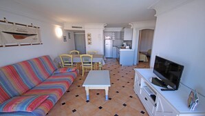 A compact living space with a sofa, a small dining table, chairs, a kitchen area, and a television. - Apartment for 4/5 people – Air conditioning – Wifi – Pool residence – Sainte Maxime –... (STE MAXIME)
