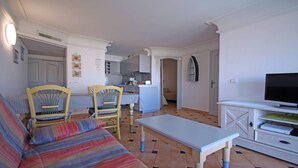 A compact living space with a sofa, two chairs, a small dining table, a television, and a kitchenette. - Apartment for 4/5 people – Air conditioning – Wifi – Pool residence – Sainte Maxime –... (STE MAXIME)