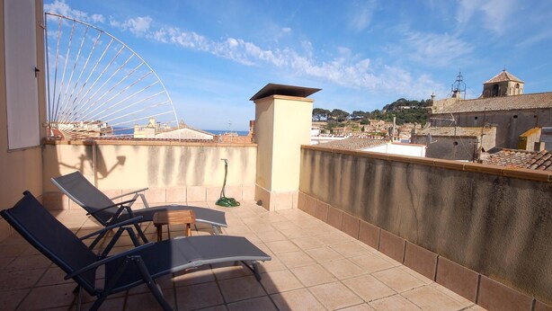 A rooftop terrace with two lounge chairs, a small table, and a view of a cityscape and the sea. - CENTRIC APARTMENT with POOL in TOSSA (Tossa de Mar)