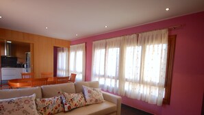 A living room with a beige sofa, floral cushions, a wooden dining table, and chairs. - CENTRIC APARTMENT with POOL in TOSSA (Tossa de Mar)