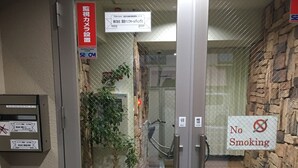 Ein Hotel Eingangsbereich mit Schildern für Überwachungsbereich, Rauchverbot und einer Überwachungskamera.