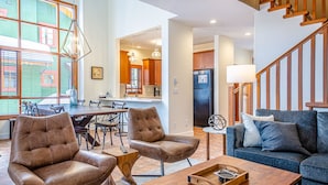 Un vaste salon comprenant un coin repas, une cuisine à l’arrière-plan et un escalier.