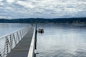 A pier extending into calm water with a boat docked at the end.