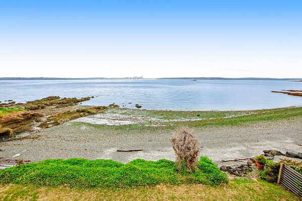 A coastal landscape with a sandy beach, rocky outcrops, and a calm body of water.