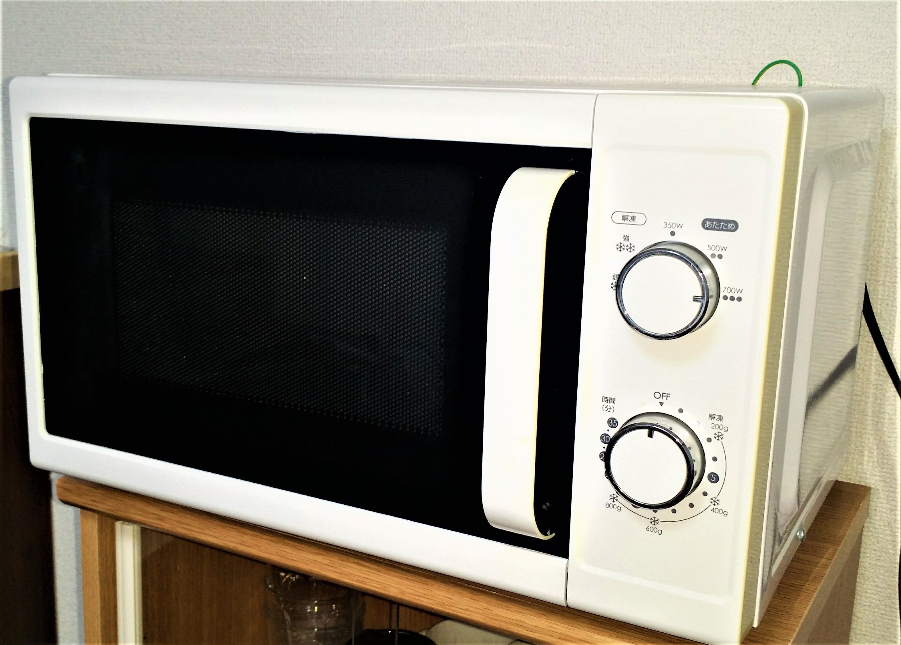 A white microwave oven with two dials on the right side, one labeled with power settings and the other with weight settings.