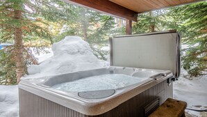 A hot tub with a wooden deck and a snow-covered ground. - Excellent multi level 2 bedroom + den townhouse, close to Morrisey lift (Sun Peaks)