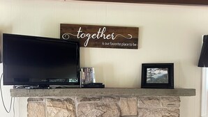 A stone fireplace with a mounted television and a framed picture above it.