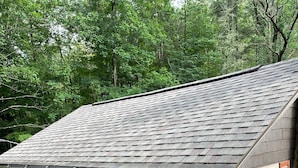 A small, single-story building with a sloped roof, a window with shutters, and an air conditioning unit mounted on the exterior wall.