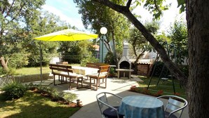 Un patio al aire libre con una mesa redonda, sillas y un paraguas amarillo.