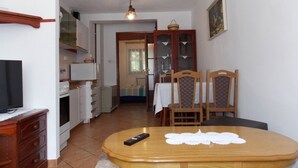 Un espacio habitable compacto con comedor, kitchenette y televisor.