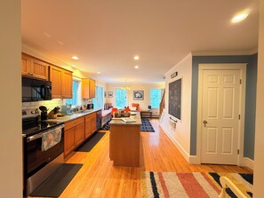 A modern kitchen with wooden cabinets, a built-in oven, and a central island. - The Round Pond Getaway. Screened Porch · Fire Pit · Walk to Harbor (Bristol)