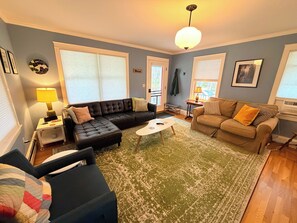 A living room with a sectional sofa, a smaller sofa, a coffee table, and a patterned rug. - The Round Pond Getaway. Screened Porch · Fire Pit · Walk to Harbor (Bristol)
