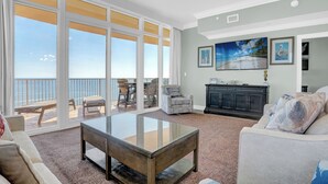 A spacious living room with a glass coffee table, a sofa, and a view of the ocean through large windows. - Phoenix Orange Beach 2006 by Liquid Life (Orange Beach)