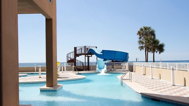 A swimming pool with a water slide, palm trees, and a clear sky. - Phoenix Orange Beach 2006 by Liquid Life (Orange Beach)