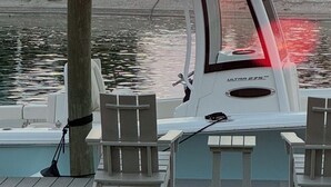 En lystbådehavn med en båd i havnen, en strand og en solnedgang i baggrunden.