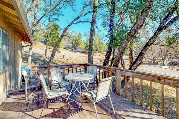 Enjoy a serene outdoor space with a round table and four chairs, surrounded by lush trees and a clear sky.