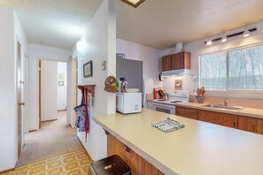 Kitchen features a central island with a sink and stove, flanked by cabinets, and a window for natural light.