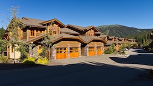 Una grande costruzione in stile baita di legno, con diverse porte per garage e un vialetto.