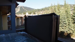 A hot tub with a view of a mountain and forest. - Upper floor 2 bedroom condo with courtyard view and easy access to ski runs (Sun Peaks)
