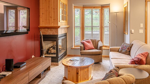 Un salon chaleureux avec une cheminée, des meubles en bois et de grandes fenêtres.