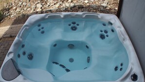 Un bain à remous doté d’un panneau de commande, entouré d’un espace extérieur rocheux.