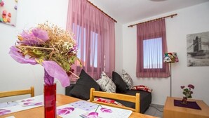 A cozy living room with a wooden table, a red vase with flowers, and a sofa with cushions. - Apartment in Njivice with Seaview, Balcony, Air condition, WIFI (4687-1) (Njivice)