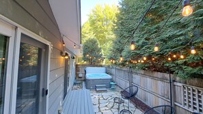 Een terras met een jacuzzi, buitenmeubels en lichtjes.