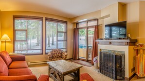 Een gezellige woonkamer met een open haard, een bank, een fauteuil en een televisie.