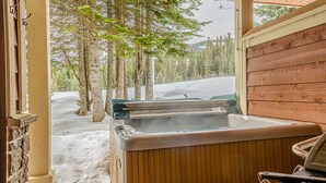 Een hottub in een houten blokhut met uitzicht op een besneeid landschap.