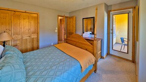 Un dormitorio con cama, mesita de noche, espejo y puerta que da a un balcón.