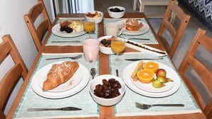 A breakfast table with plates of food, a glass of orange juice, and a bowl of dates. - Blue & Green Apts - Dassia, Corfu 4 (Corfu)