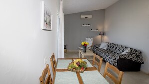 A compact living space with a dining area, a sofa, and a small table with a fruit basket. - Blue & Green Apts - Dassia, Corfu 4 (Corfu)