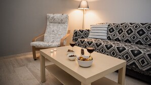 A cozy living room with a patterned sofa, a chair, a table with snacks and drinks, and a lamp providing soft lighting. - Blue & Green Apts - Dassia, Corfu 4 (Corfu)
