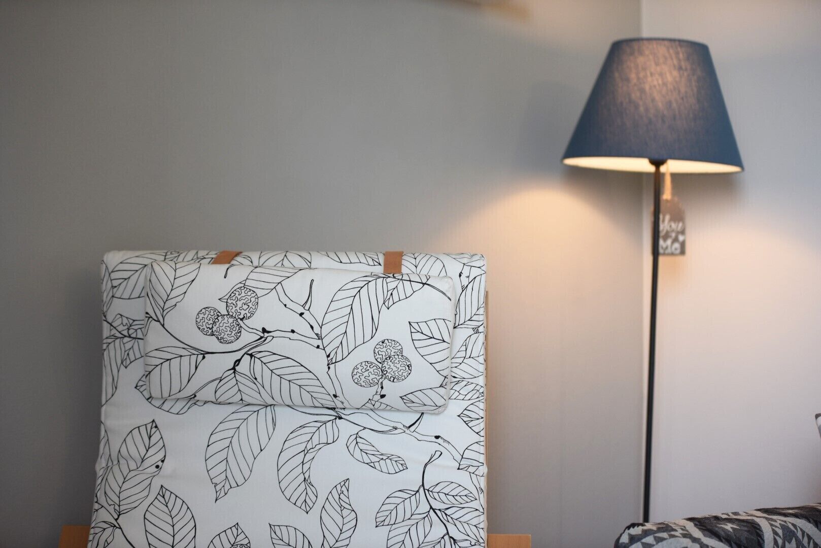 Habitación con una obra de arte en la pared con estampado de hojas, una lámpara de pie y un felpudo con estampado de cebra.