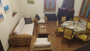 A cozy living area with a sofa, two armchairs, a coffee table, and a dining table set for four. - A cute, homey cottage overlooking the Apuan Alps . A perfect place to relax in. (Casone Carpinelli)