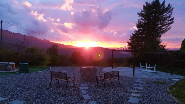 A sunset over a mountainous landscape with a gazebo, two benches, and a stone pathway. - A cute, homey cottage overlooking the Apuan Alps . A perfect place to relax in. (Casone Carpinelli)