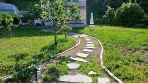 A garden pathway leading to a building with a balcony. - A cute, homey cottage overlooking the Apuan Alps . A perfect place to relax in. (Casone Carpinelli)