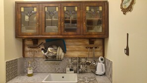 A kitchen with wooden cabinets, a sink, and a dish rack. - A cute, homey cottage overlooking the Apuan Alps . A perfect place to relax in. (Casone Carpinelli)