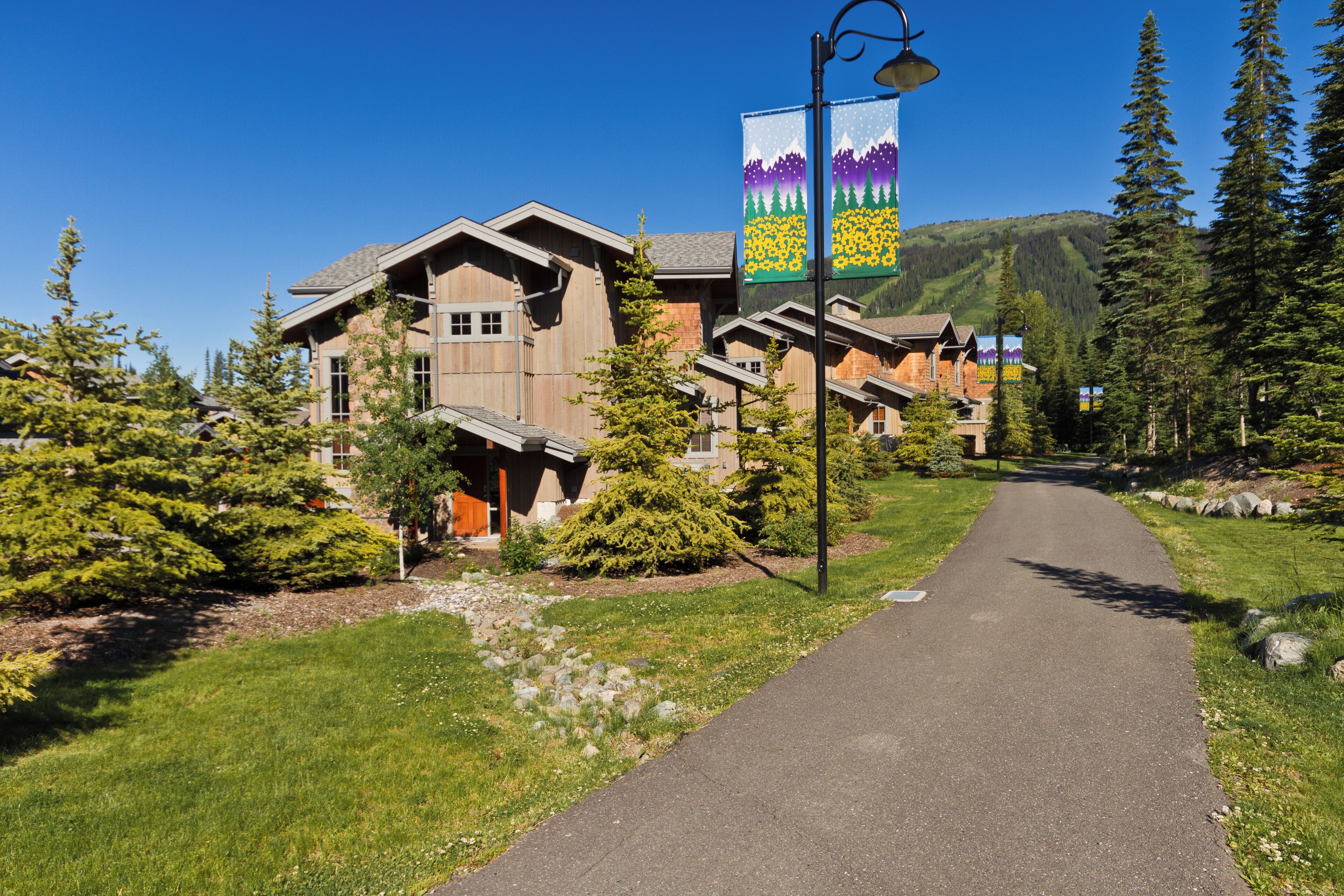 A row of wooden buildings with a paved walkway in front.