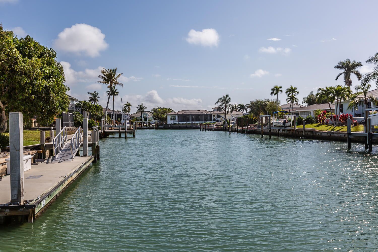 Un port de plaisance avec des quais, un bateau et des immeubles résidentiels en arrière-plan.