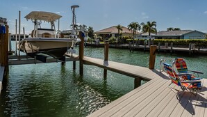 Un port de plaisance avec un bateau amarré, une jetée en bois et des chaises colorées.