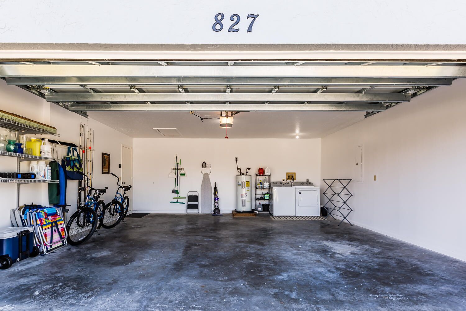 En ren og velorganiseret garage med beton gulv, cykelstativ, vandvarmer og vaskemaskine.