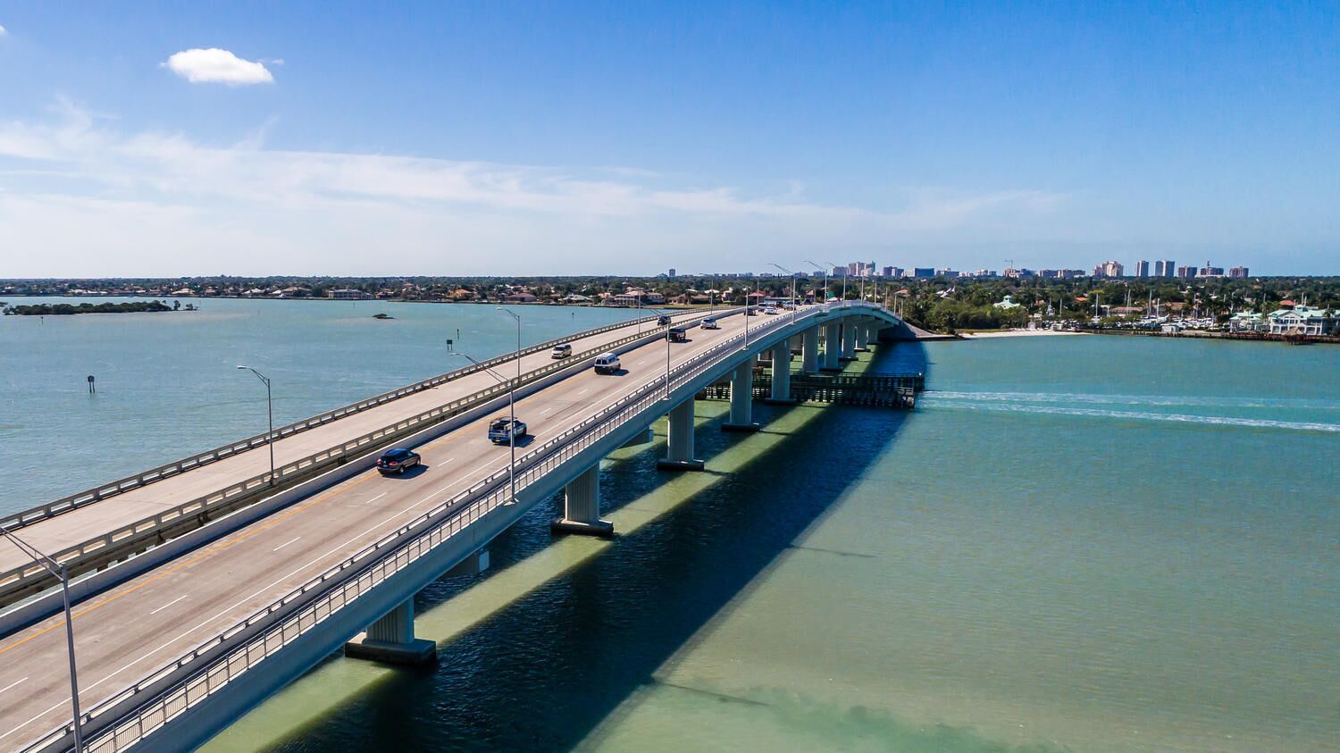 Un pont comportant plusieurs voies de circulation, enjambant une étendue d’eau, avec une vue sur la ville en arrière-plan.