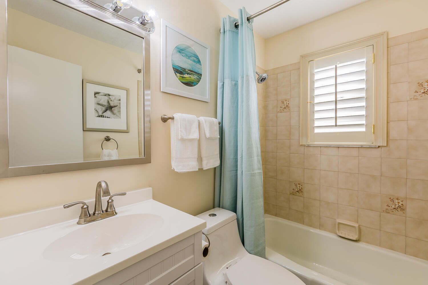 A bathroom with a sink, mirror, and shower.
