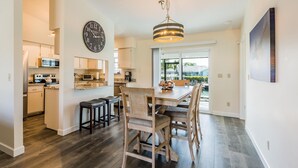 Une cuisine moderne avec un coin repas, un plancher en bois et une grande horloge au mur.