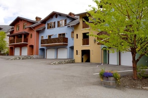 Une rangée d’immeubles à plusieurs étages, dotés de balcons et de portes de garage, qui semblent être des immeubles résidentiels ou de petits locaux commerciaux.