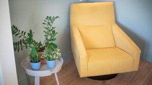 Un sillón amarillo junto a una mesita blanca con plantas en macetas.