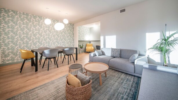 Una sala de estar moderna con sofá, mesa de comedor, sillas y una mesa de centro.