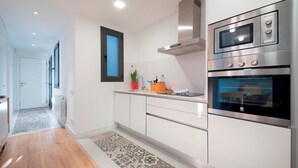 Una cocina moderna con electrodomésticos de acero inoxidable, armarios blancos y un tapete estampado.