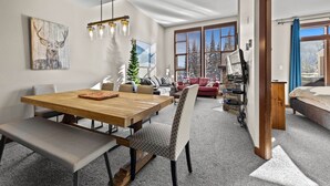 Ein modernes Wohnzimmer mit einem Holzesstisch, einer Bank und einem gemusterten Sessel.